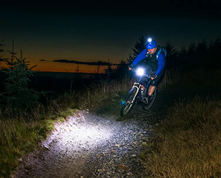 Ciclista conduciendo bicicleta de noche con luces encendidas