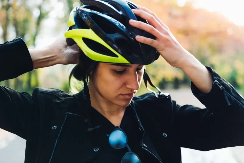 Mujer colocándose un casco de bicicleta para protección